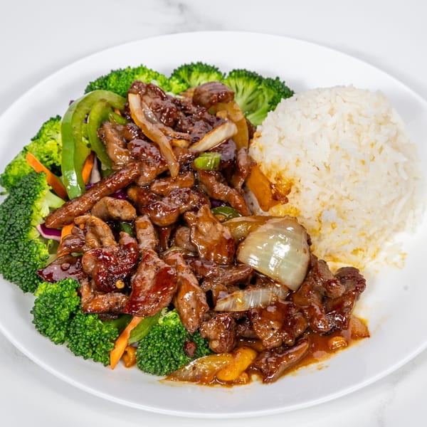 Hibachi beef with broccoli, onions, and peppers, served with white rice on a white plate.