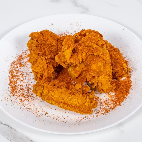 Crispy fried chicken pieces generously dusted with orange seasoning on a white plate.